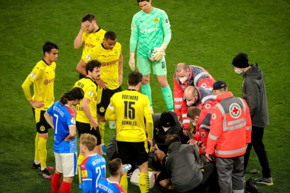 Dortmunder Spieler stehen um ihren Mannschaftskameraden Mateu Morey (verdeckt) herum, der nach einer Verletzung während des DFB-Pokal-Halbfinalspiels zwischen Borussia Dortmund und Holstein Kiel in Dortmund, Deutschland, am 01. Mai 2021 medizinisch versorgt wird.