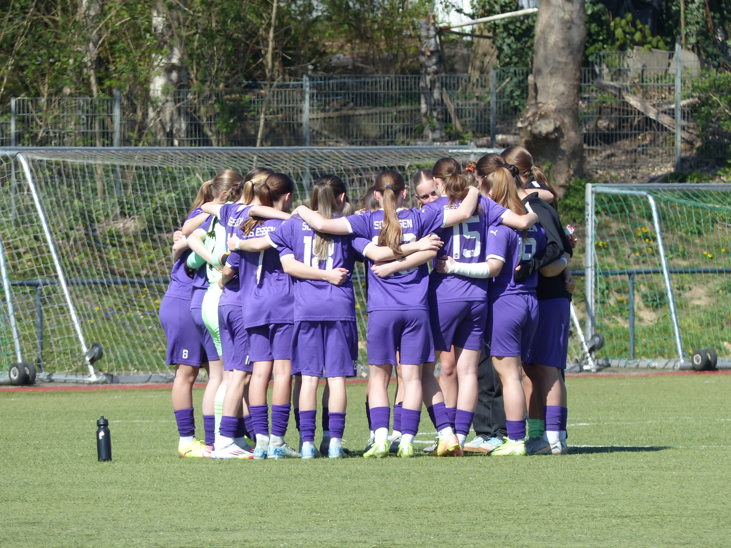 Spielerinnen der U17 der SGS Essen stehen vor einem Fußballspiel in der Regionalliga West in einem Spielerkreis.