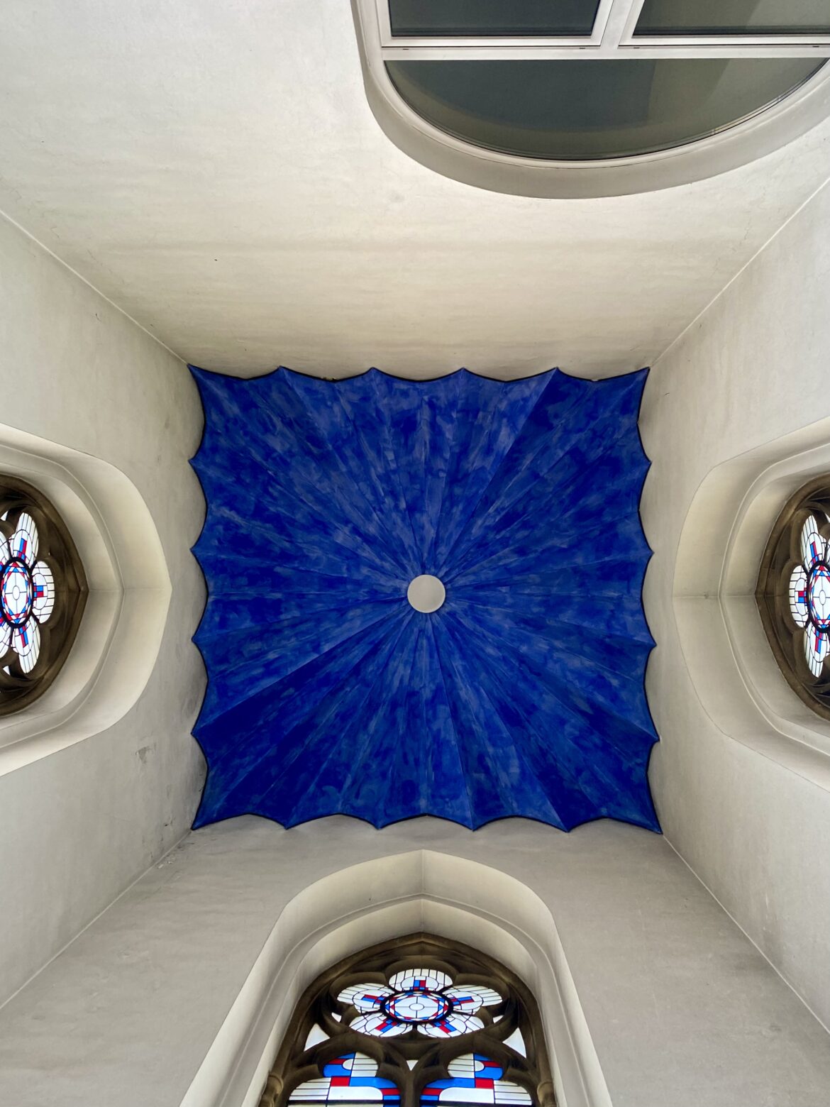 Die tiefblaue Decke eines Nebenraums in der Sankt Gertrud Kirche. An jeder Wand ist ein bisschen der Glasfenster zu sehen. Die Wände sind weiß.