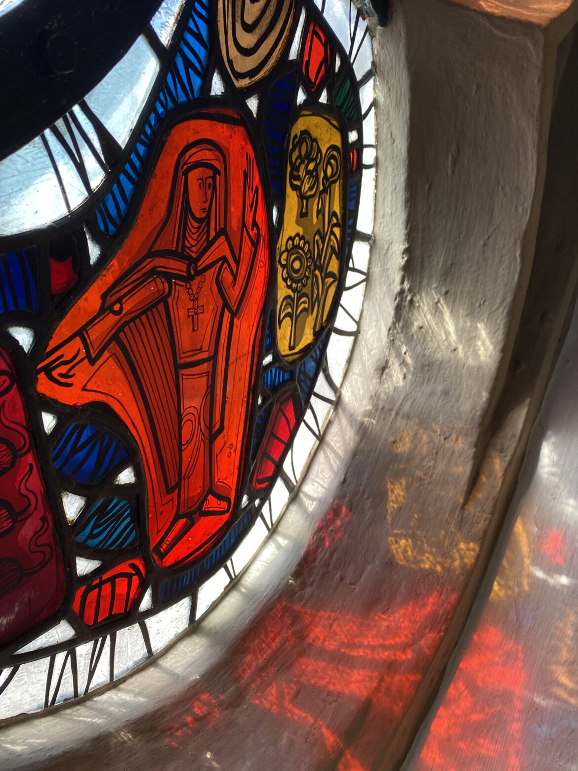 Eine Detailaufnahme eines Glasfensters der Sankt Gertrud Kirche zeigt die heilige Gertrud, wie sie Ratten bzw. Mäuse von der Ernte vertreibt