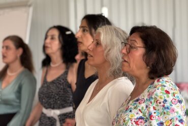 Frauen des Migrantinnen-Chors stehen nebeneinander und singen.