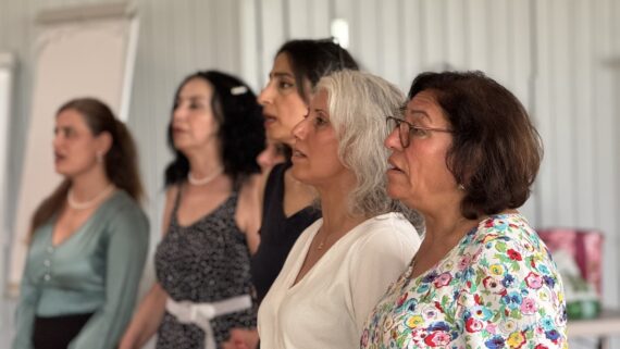 Frauen des Migrantinnen-Chors stehen nebeneinander und singen.