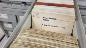 Eine handgeschriebene Karteikarte in einem Karteikasten mit Informationen zu Werken von Heinrich Heine.