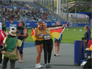 Joyce posiert mit Antonia Kinzel, die eine Deutschlandflagge über ihre Schultern hält.