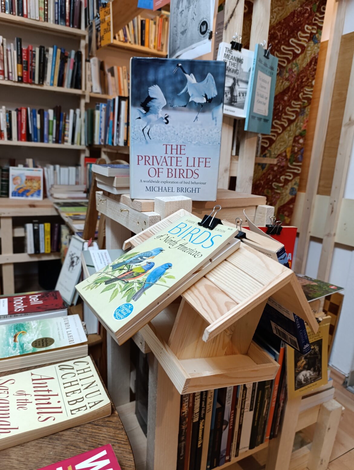 Bücer über Vögel sind an und um ein Vogelhäuschen arrangiert