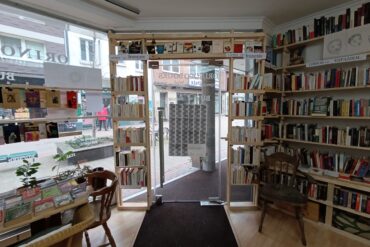 Blick von Innen auf die Ladentür des Orinoco. Die Glastür ist umgeben von Bücherregalen, die bis zur Decke gehen.
