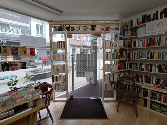 Blick von Innen auf die Ladentür des Orinoco. Die Glastür ist umgeben von Bücherregalen, die bis zur Decke gehen.