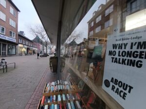 Schaufenster des Orinoco mit Büchern davor und im Fenster. In der Scheibe spiegeln sich die Gebäuder der Straße.