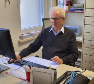 Das Foto zeigt Herrn Dr. Luckhaupt, wie er am Computer an seinem Schreibtisch sitzt